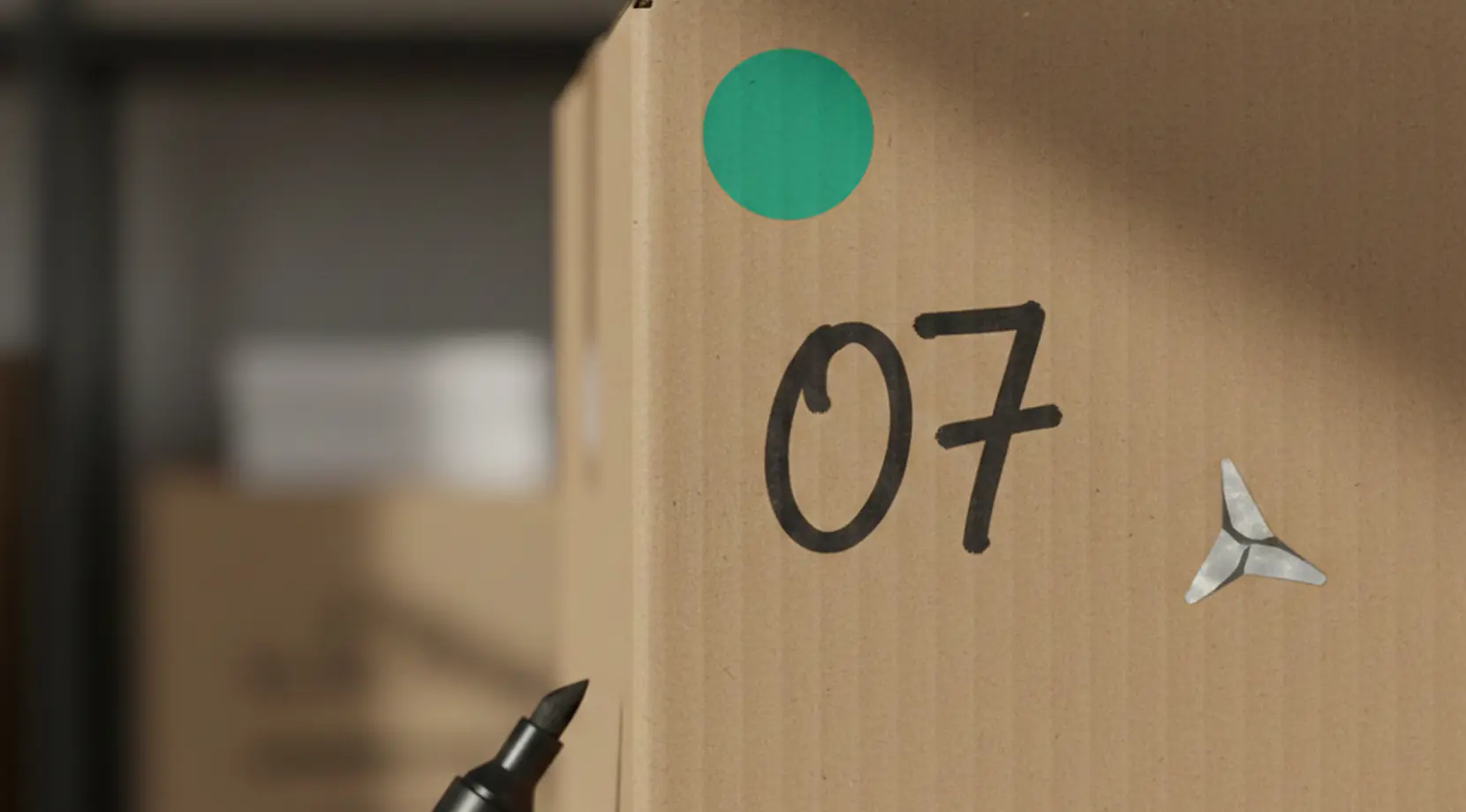 Close-up of a labeled moving box with a green sticker and marker beside it, showing how to pack for a long distance move with a simple numbering system.
