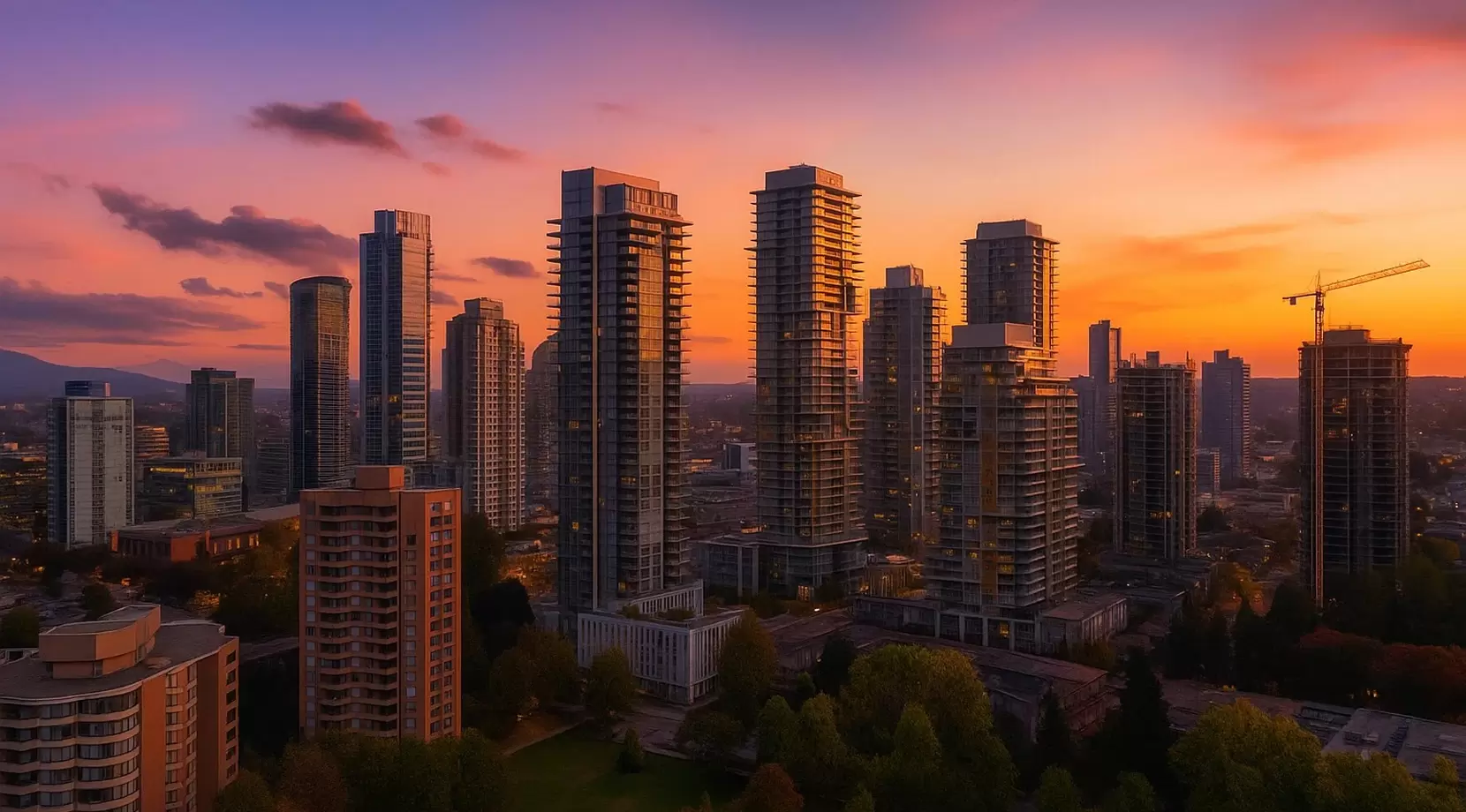 Golden-hour skyline of slender residential high-rises glowing against an orange-purple sky. Parkland and mid-rise blocks sit below, with a few cranes and early window lights dotting the scene.