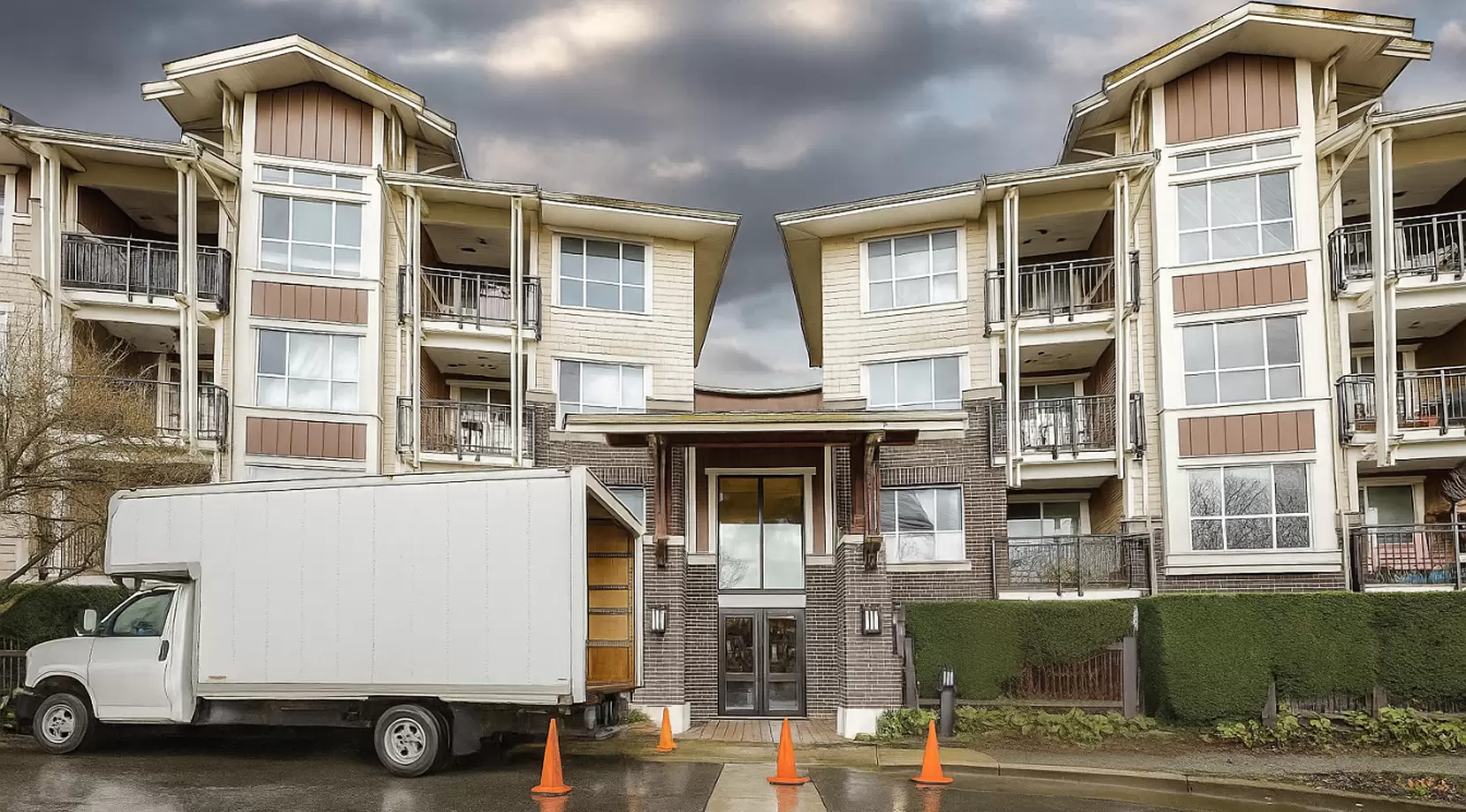 Moving truck parked with safety cones outside a Burnaby apartment complex, a clear visual for a moving checklist and moving to a new apartment.